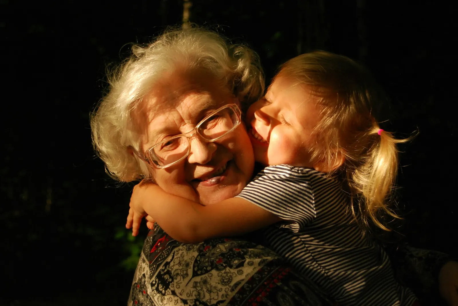 A grandmother smiling as her granddaughter hugs her